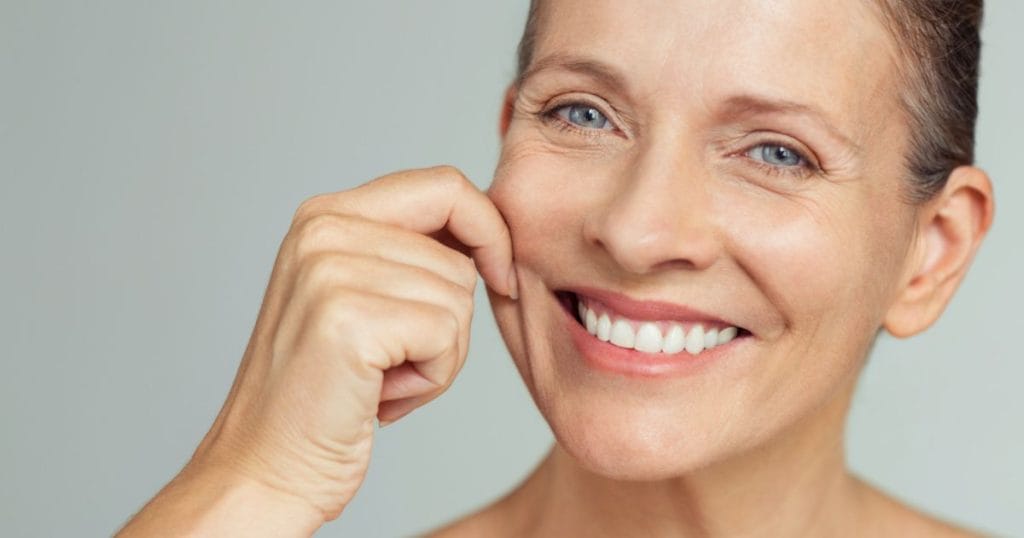 donna che si pizzica la pelle migliorata dopo l'assunzione di integratori di retinolo