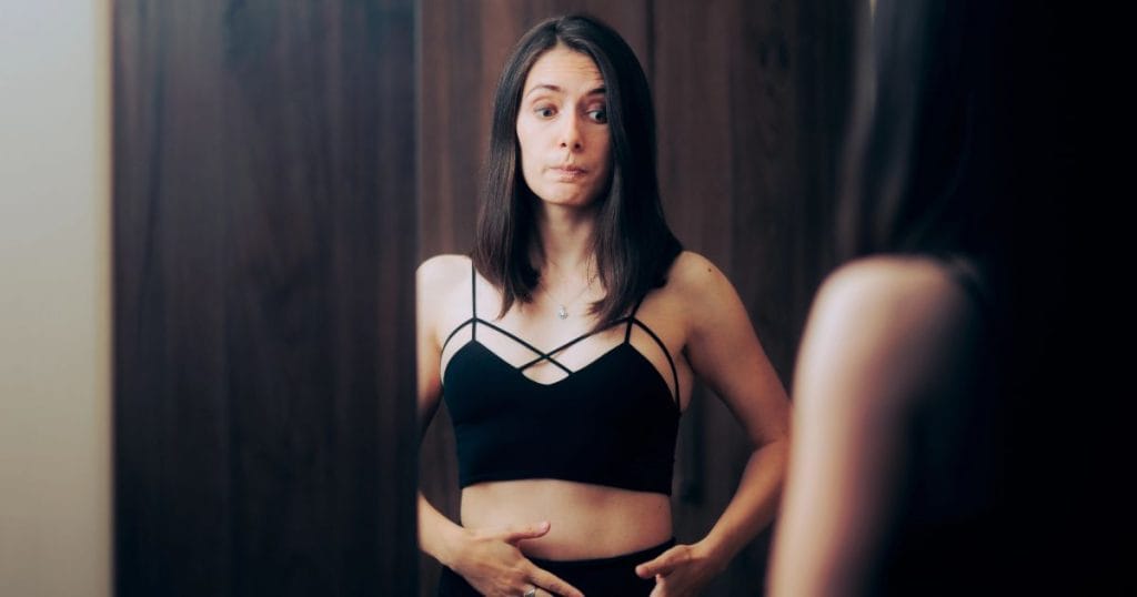 donna davanti allo specchio si chiede cosa fare per eliminare il gonfiore addominale