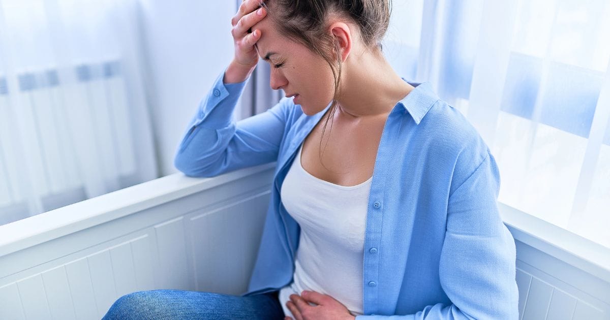 donna seduta si tiene la pancia con una smorfia di dolore